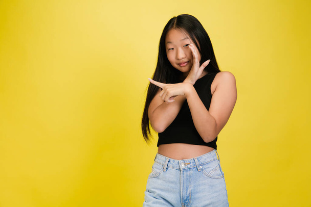 Portrait of young asian girl isolated on yellow studio background - Foto, Imagem