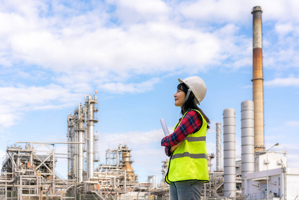 Asian woman engineer work control at power plant energy industry manufacturing oil refinery. Engineering check plant with blueprint. - Photo, Image