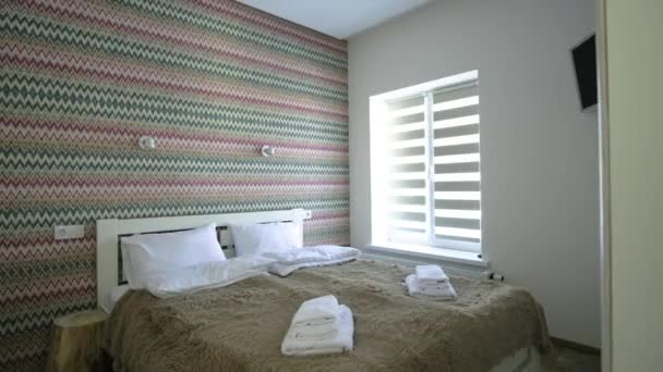 Interieur van een ruime hotelkamer met fris linnengoed op een groot tweepersoonsbed. Gezellige eigentijdse kamer in een modern huis. - Video