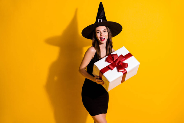 Portrait of her she nice attractive pretty lovely glad cheerful cheery lady wizard holding in hands big large giftbox congrats occasion isolated over bright vivid shine vibrant yellow color background - Fotoğraf, Görsel