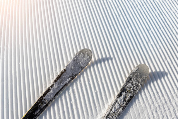 Панорамна точка зору ноги лижника на спуску починають пряму лінію рядів, що свіжо підготовлені доглянутими схилами лижного схилу на яскравому фоні блакитного неба. гірський ландшафтний європейський зимовий курорт
 - Фото, зображення