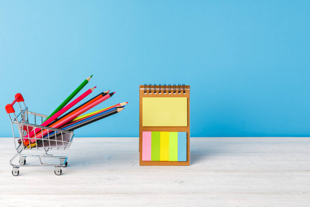 School supplies on wooden desk against blue background - Foto, Imagen