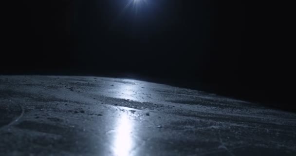 Close up of feet of hocky player or skater on skaters fast sliding on icy surface in darkness. Skating on ice arena in light of single spotlight lamp. Hockey match concept. - Footage, Video