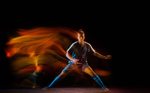 Football or soccer player on black background in mixed light, fire shadows - Fotografie, Obrázek