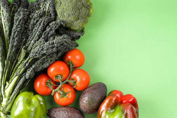 緑の背景に新鮮な有機生野菜。ダイエット、デトックスと健康食品のコンセプト、サラダのための成分のトップビューフラットレイアウト. - 写真・画像