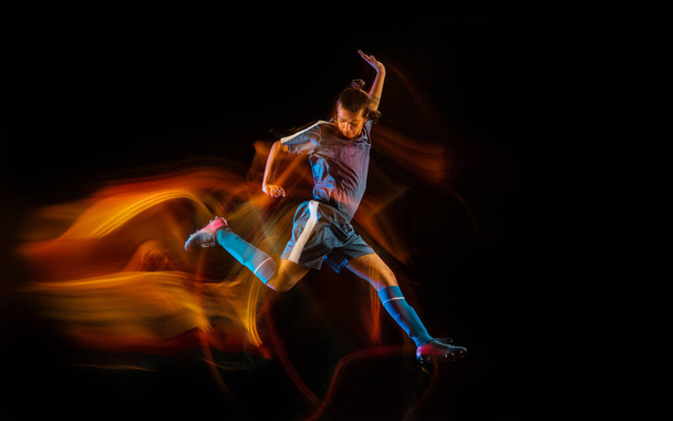 Voetbal of voetbal speler op zwarte achtergrond in gemengd licht, vuur schaduwen - Foto, afbeelding