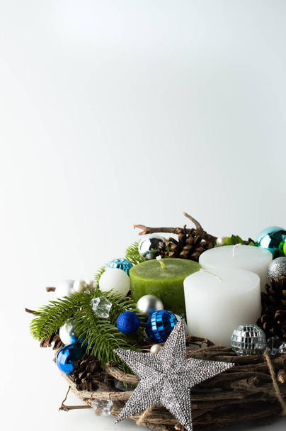 Christmas composition with three candles with festive decor in silver blue tones and a vine on a white background. - Foto, immagini