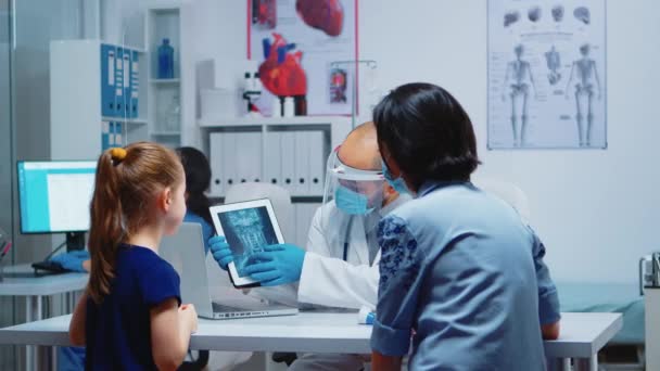 Lekarz wyjaśniający promieniowanie rentgenowskie za pomocą tabletek - Materiał filmowy, wideo