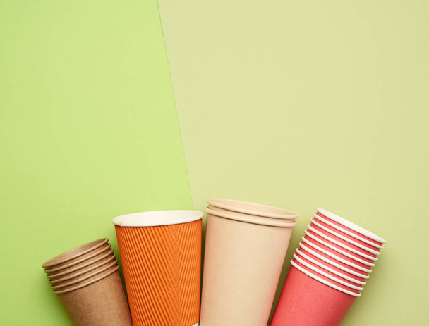 brun, papier rouge gobelets jetables sur fond vert, plat, concept respectueux de l'environnement, zéro déchet  - Photo, image