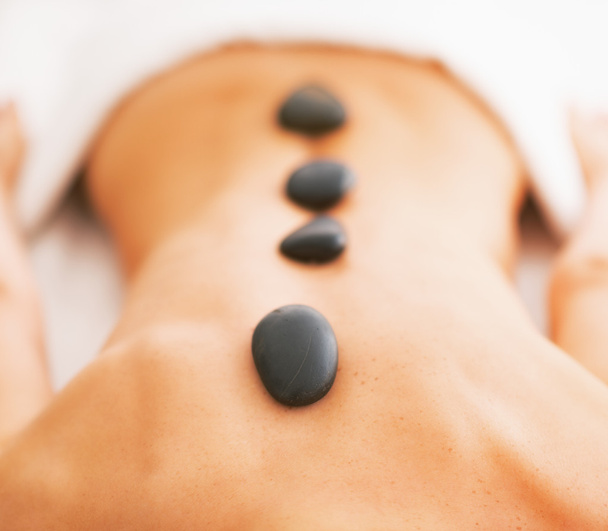 Closeup on young woman receiving hot stone massage - Photo, image