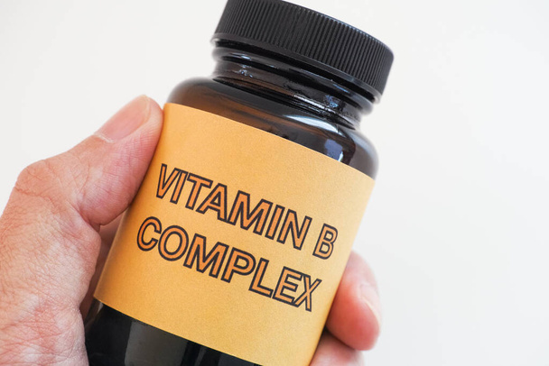 Person holding a bottle of Vitamin B Complex. Close up. - Foto, imagen