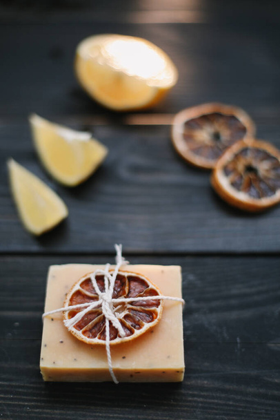 Natural handmade soap with dried slices of oranges on a dark background. Body and skin care. Flat lay. Space for text, top view - Fotografie, Obrázek