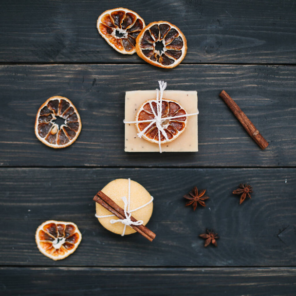 Natural handmade soap with dried slices of oranges on a dark background. Body and skin care. Flat lay. Space for text, top view - Photo, image