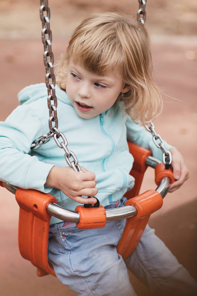 A mozgássérült kislány játszik a játszótéren. - Fotó, kép