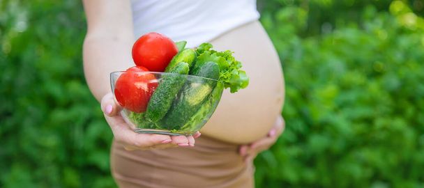 Egy terhes nő zöldségekkel a kezében. Szelektív fókusz. élelmiszer. - Fotó, kép
