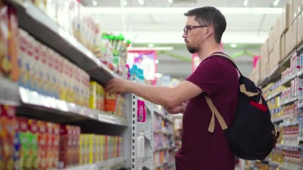 Le jeune homme achète de la nourriture pour bébé au supermarché - Séquence, vidéo