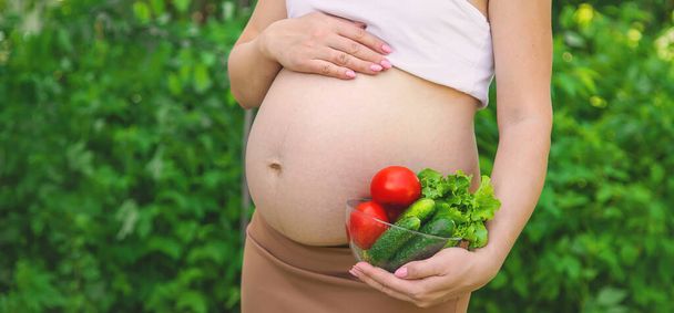 A pregnant woman with vegetables in her hands. Selective focus. food. - Photo, Image