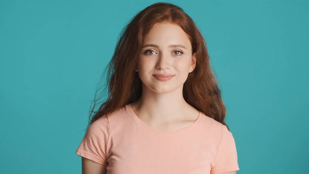 Beautiful smiling redhead girl intently looking in camera over colorful background - Фото, зображення