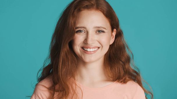 Pretty cheerful redhead girl happily looking in camera over colorful background - Photo, Image