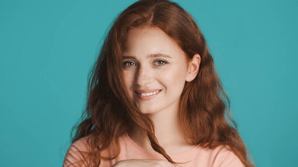 Pretty charming redhead girl cutely posing on camera over colorful background - Zdjęcie, obraz