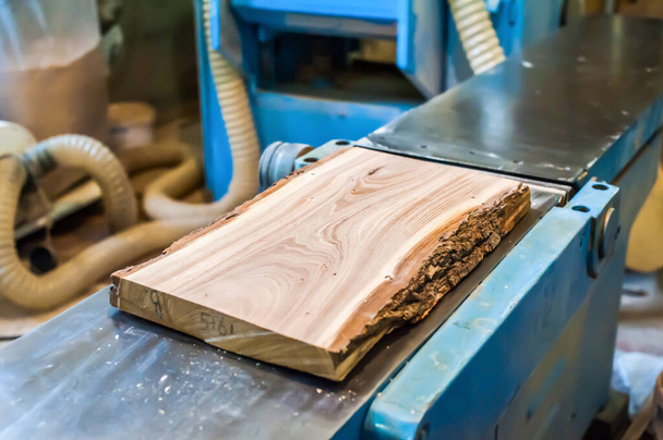 placa de madeira laje encontra-se em uma grande máquina de trabalhar madeira em uma oficina de carpintaria - Foto, Imagem