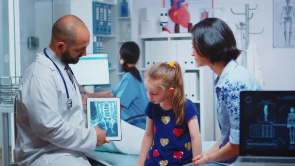 Männlicher Kinderarzt überprüft Knochen-Röntgen auf Tablet - Filmmaterial, Video