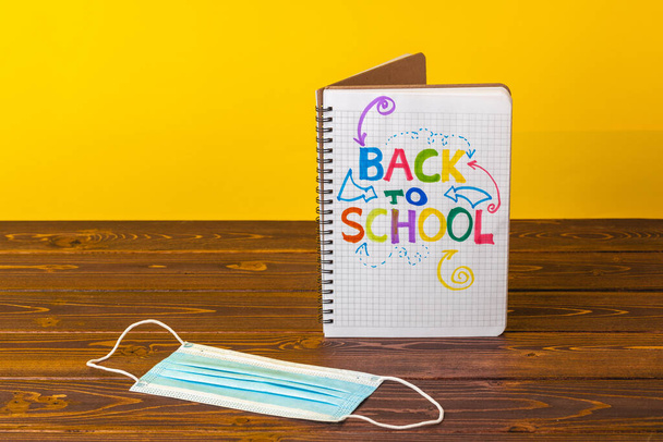 Back to school concept with notepad and medical face mask - Fotó, kép