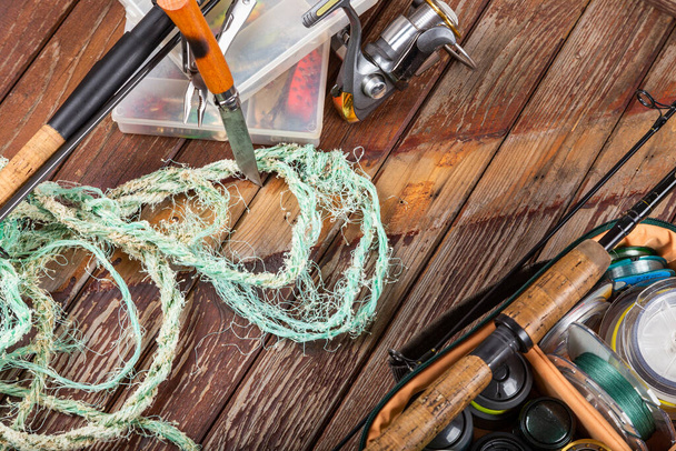 Vari tipi di pesca con canna e mulinelli su fondo marrone legno. Mockap per pubblicità ed editoria. - Foto, immagini