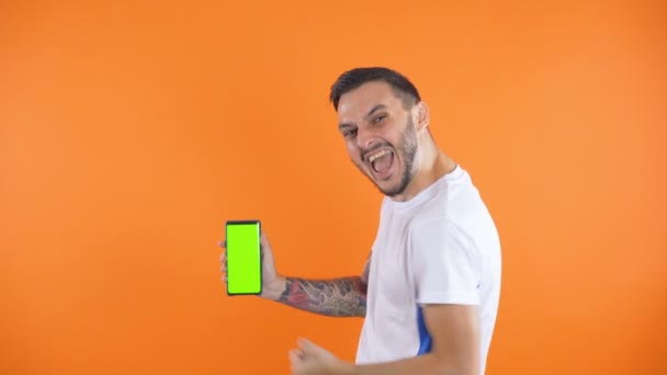 счастливый футбольный болельщик или игрок празднуя и показать зеленый экран телефона - Кадры, видео