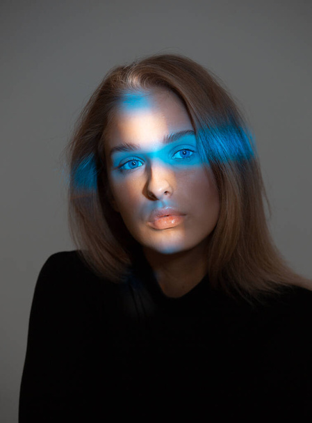 Trendy portrait of beautiful girl with neon light on face isolated on gray background in studio - Foto, Imagen