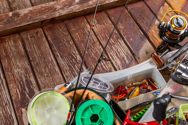 Diferentes tacos de pesca con caña y carretes sobre fondo marrón madera. Mockap para publicidad y publicación. - Foto, imagen