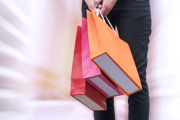 Mano de mujer que lleva bolsas de compras con fondo efecto zoom. felicidad, consumismo, venta y concepto de personas. - Foto, Imagen