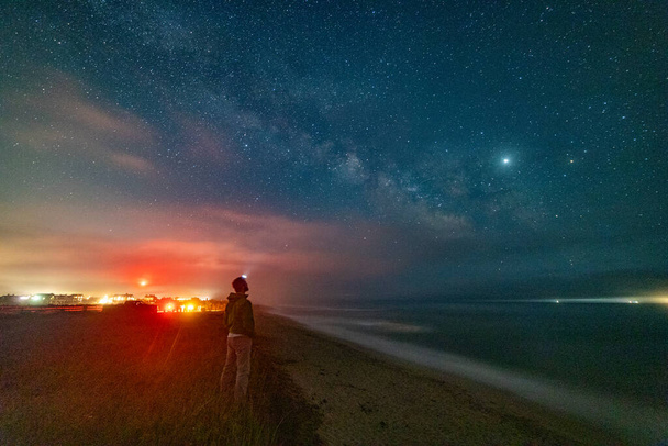 Uomo in piedi lungo la spiaggia guardando Milkyway Galaxy sopra l'oceano. - Foto, immagini