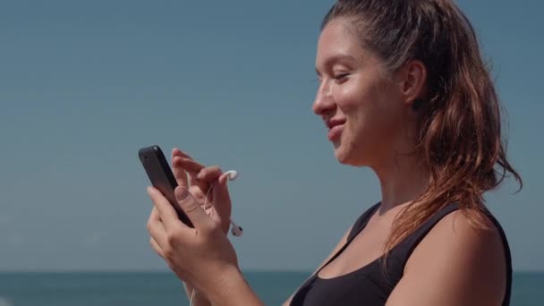 ジョギング前に携帯電話で音楽を選択する高潔な女性 - 映像、動画