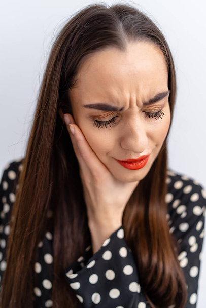 Suffering from toothache. Beautiful young woman suffering from toothache, standing against white background. Dental care concept. People emotions. - Foto, imagen