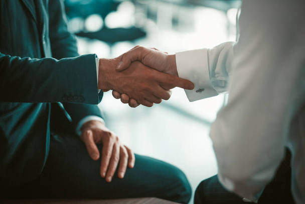 Employees shake hands at a business meeting. Making a deal between partners. Two men in suits. High quality photo - Zdjęcie, obraz