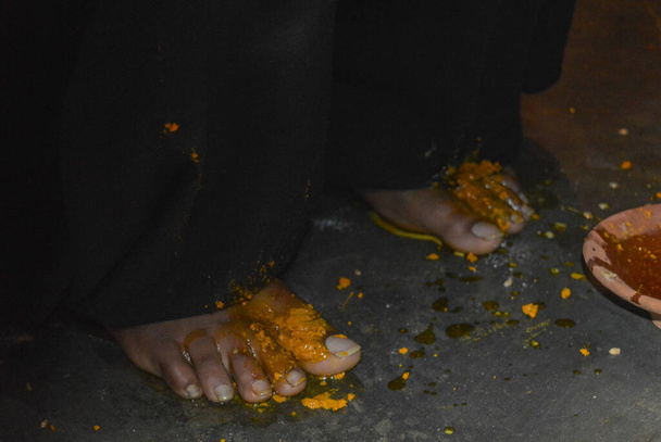 κοντινό πλάνο των ποδιών της νύφης σε χαλντί (κουρκουμά) τελετή σε ένα από τα τελετουργικά σε ινδικό γάμο. - Φωτογραφία, εικόνα