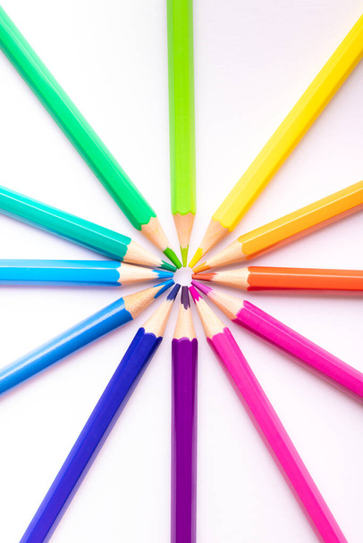 Rueda de color compuesta por lápices de colores colocados sobre un fondo blanco.  - Foto, imagen