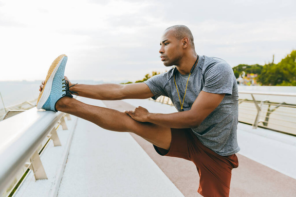 Confident young african sports man stretching on the bridge - Valokuva, kuva