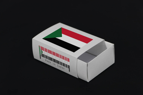 Bandeira do Sudão na caixa branca com código de barras e a cor da bandeira da nação no fundo preto, embalagem de papel para colocar jogo ou produtos. Conceito de comércio de exportação do Sudão. - Foto, Imagem