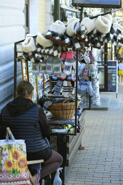 Woman street seller sitting in front of trays with handmade warm clothes. Kyiv, Ukraine - Photo, Image