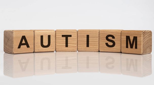 Wooden cubes with word autism on white glossy background. - 写真・画像