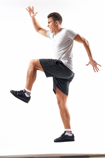 Athletic man on a light background in full growth and jogging charging shorts sneakers t-shirt - 写真・画像