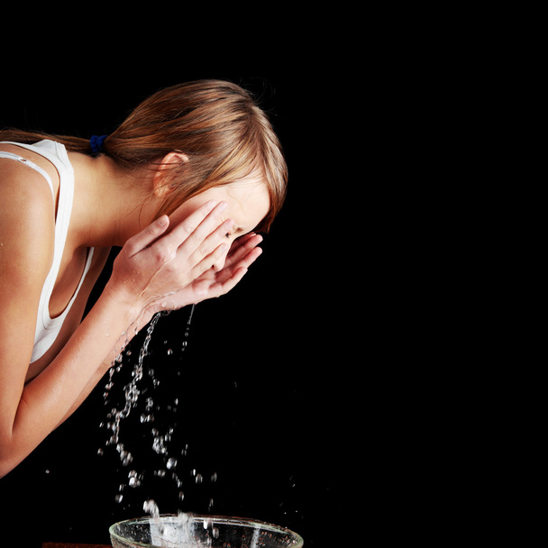 Teen girl washing her face with water - 写真・画像