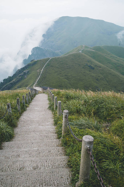 Fußweg windet sich auf Bergrücken mit wolkenverhangener Landschaft auf dem Wugong-Berg in Jiangxi, China - Foto, Bild