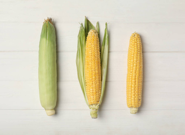 Corn cobs on white wooden table, flat lay - Foto, immagini