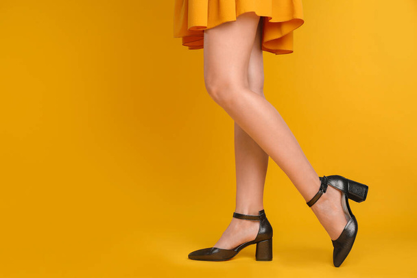 Woman wearing stylish shoes on yellow background, closeup. Space for text - 写真・画像