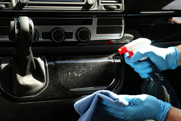 Man in gloves cleaning car dashboard with disinfectant spray and rag, closeup. Preventive measure during coronavirus pandemic - Foto, imagen