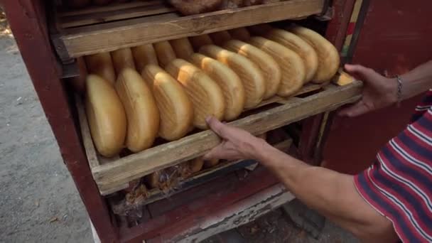 Mies toimittaa leipää kaupungin kaupoille, kun hän vetää ulos auton rungosta puinen tarjotin täynnä tuoretta leipää herkullista leipää. - Materiaali, video