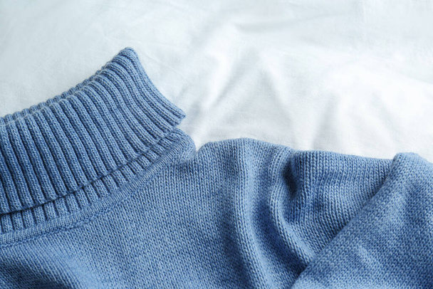 Stylish knitted sweater on white fabric, closeup - Valokuva, kuva
